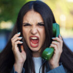 Young woman using a smart phone and a vintage analog phone